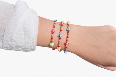 Armband aus bunten Glasperlen und goldfarbenen Edelstahlperlen, sowie gestreiften Spacern aus Polymer. 
