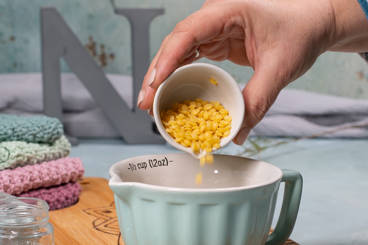 Bienenwachspl&auml;ttchen werden in eine Tasse gesch&uuml;ttet. 