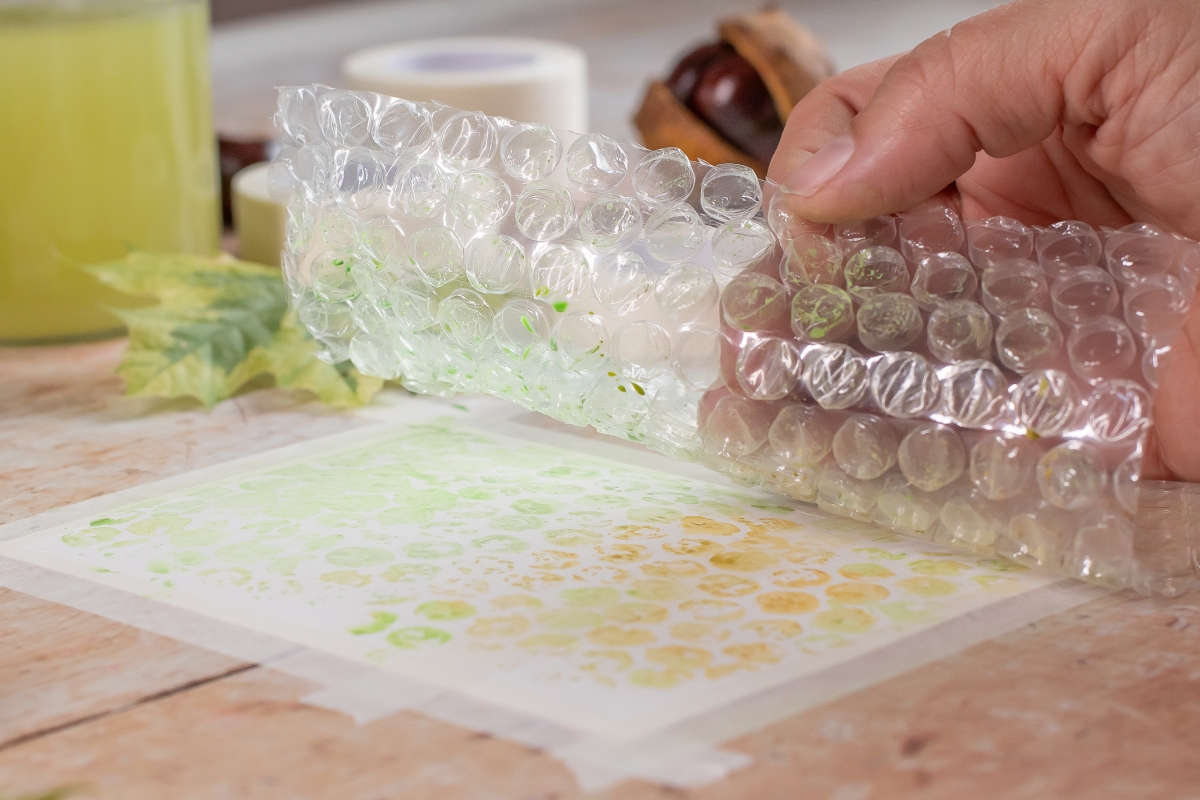 Luftpolsterfolie mit Farbe drauf wird auf ein Blatt Papier gedr&uuml;ckt.